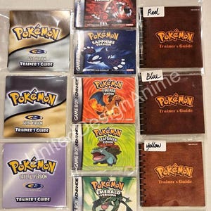 May include: A collection of Pokémon video game instruction booklets and Trainer's Guides. The booklets include Ruby, Sapphire, FireRed, LeafGreen, and Emerald versions. The Trainer's Guides are labeled Red, Blue, and Yellow.