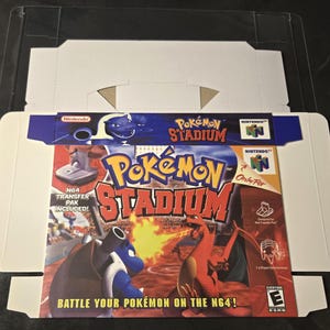 May include: A Pokémon Stadium video game box for the Nintendo 64. The box features a colorful design with the game's title and images of Pokémon characters. The box includes the text "N64 Transfer Pak Included!" and "Battle Your Pokémon on the N64!"