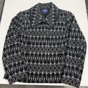 May include: A black and gray patterned jacket with a collared neckline. The jacket features a geometric design with diamond and arrow-like shapes. The brand name "Pendleton" is visible on a tag inside the collar.