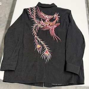 May include: Black button-down shirt with long sleeves. The back of the shirt features an embroidered phoenix design in red, pink, yellow, and white. The shirt has a collar and buttoned cuffs.