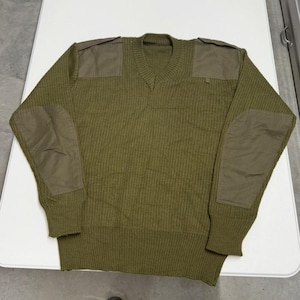 Könnte beinhalten: Olivgrüner V-Ausschnitt-Pullover mit verstärkten Aufnähern an Schultern und Ellbogen. Der Pullover hat eine gerippte Strickstruktur und ein klassisches Design. Ein strapazierfähiges und warmes Kleidungsstück für kühlere Tage.