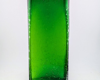 May include: A rectangular, emerald green glass vase. The vase has a slightly textured surface with small air bubbles throughout. The edges are defined and the overall shape is modern and minimalist. The vase is empty and sits against a white background.