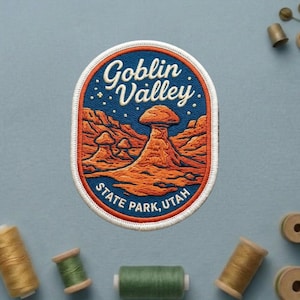 May include: Embroidered patch featuring a landscape of Goblin Valley State Park, Utah. The patch has a blue background with the words "Goblin Valley" in white script. The landscape is in shades of orange and brown.