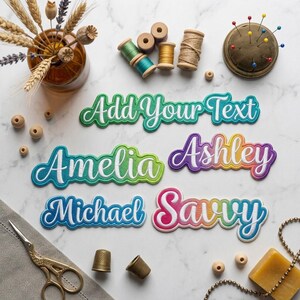 May include: Custom embroidered name patches featuring gradient colors and white script lettering. The patches display the text Add Your Text, Amelia, Ashley, Michael, and Savvy, arranged with sewing supplies including spools, pins, and scissors.