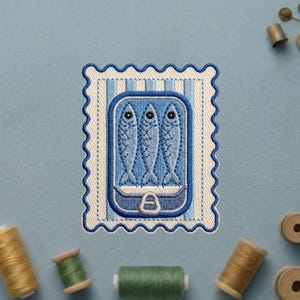 May include: A rectangular embroidered patch with a scalloped edge featuring a blue and white striped background. The center displays an open tin can containing three blue fish with visible scales and black eyes, finished with a silver pull tab.