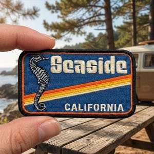 May include: A rectangular embroidered patch with a blue background featuring a black and white seahorse on the left. The text Seaside is in white above a diagonal orange, yellow, and white stripe, with the word CALIFORNIA in white below.