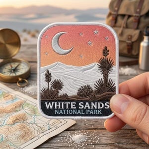 May include: A rectangular embroidered patch featuring a desert landscape with white sand dunes, dark brown desert plants, and a crescent moon with stars against a gradient orange sky. The text WHITE SANDS NATIONAL PARK is printed in white.
