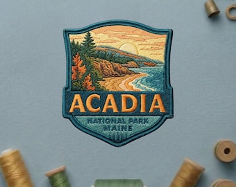 May include: An embroidered patch featuring a landscape of Acadia National Park in Maine. The design shows a coastline with trees, a sandy beach, and a sunlit sky in shades of orange, blue, and green. The text ACADIA NATIONAL PARK MAINE is stitched.
