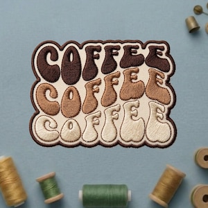 May include: Embroidered patch with the word "COFFEE" in a retro font. The word is stacked three times, with each word in a different shade of brown and beige. The patch has a brown border and is on a light beige background.