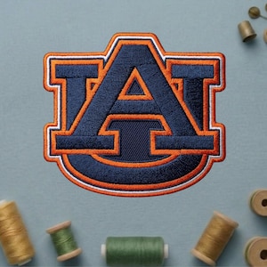 May include: Embroidered patch featuring the letter "A" in navy blue with orange and white trim. The patch has a unique shape and is surrounded by spools of thread in various colors, suggesting a crafting theme.