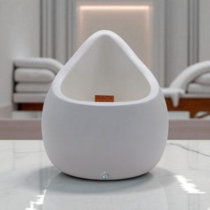 May include: A white, teardrop-shaped candle holder with a wooden wick. The holder has a smooth, matte finish and a small, decorative accent at the base. The candle holder is sitting on a marble surface.