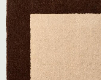 Tappeto in lana trapuntato a mano con bordo beige e marrone, stile moderno e minimalista.
