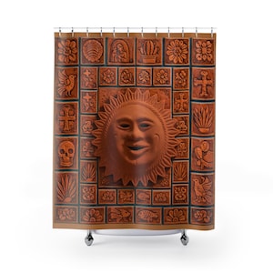 Może przedstawiać: Terrakotowa zasłona prysznicowa z centralną uśmiechniętą twarzą słońca otoczoną różnymi kafelkami reliefowymi. Kafelki przedstawiają kwiaty, krzyże, ptaki i inne elementy dekoracyjne. Zasłona jest przeznaczona do zawieszenia na metalowym drążku.