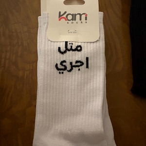 May include: White socks with the brand name "Kami socks" printed on the tag. The socks have text in Arabic. The socks are one size.