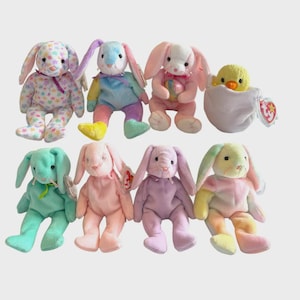 May include: A selection of plush Easter toys, featuring several bunnies with long ears and a chick in an egg. The bunnies are in pastel shades and patterns. Each toy has a tag attached.