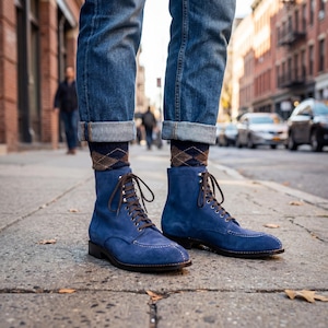 Könnte beinhalten: Blaue Wildlederstiefel mit braunen Schnürsenkeln und einem genähten Design. Die Stiefel werden mit einer blauen Jeans und Argyle-Socken kombiniert. Die Stiefel sind etwa 15 cm hoch.