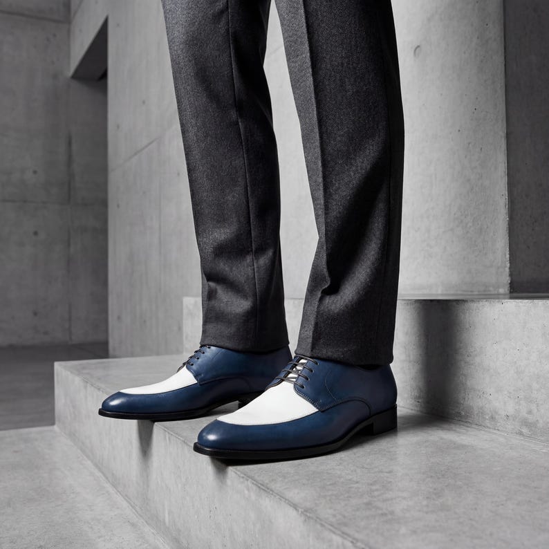 Man wearing blue and white spectator shoes with dark denim jeans and blue argyle socks.