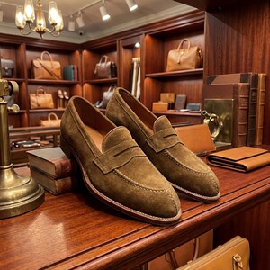Goodyear welted mens suede loafers displayed on a wooden shelf in a high-end boutique