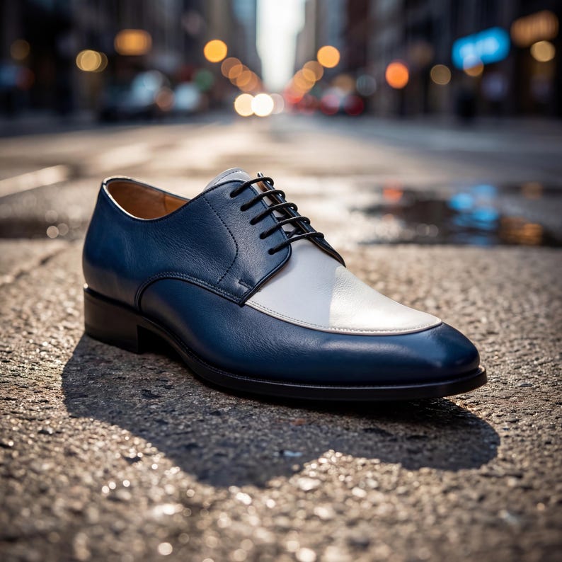 Close up of men's blue dress shoes with white leather vamp and black laces on a city street.