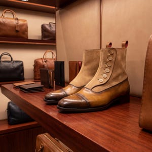 High-angle view of handmade tan and brown button boots showing the intricate stitching and premium materials.