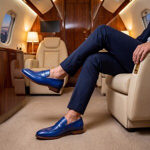 Close-up of blue leather penny loafers worn by a man in a luxury private jet interior with tan leather seating.