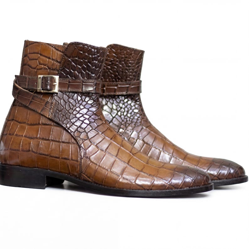 Handmade luxury men's footwear in brown crocodile grain against a clean white background.