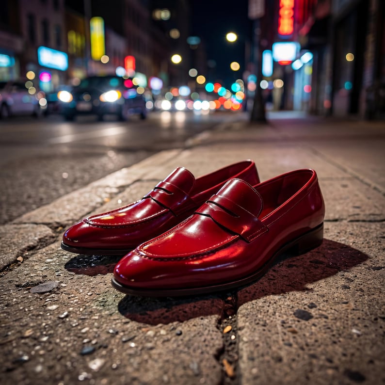 Low-angle shot of red leather loafers on a cobblestone street at night with cinematic city lights.