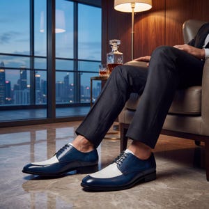 Men's blue and white leather spectator shoes worn with a black suit in a luxury high-rise office.