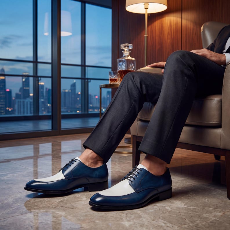 Men's blue and white leather spectator shoes worn with a black suit in a luxury high-rise office.