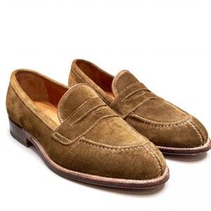 Detail shot of the penny loafer strap and high-quality suede texture on a white background.