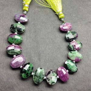 Puede incluir: Un collar de piedras preciosas ovales facetadas en tonos verdes y magenta. Las piedras preciosas est&aacute;n ensartadas con peque&ntilde;as cuentas blancas. El collar est&aacute; rematado con una borla verde lima.