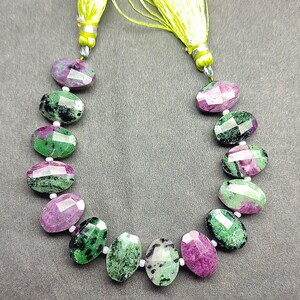 Puede incluir: Un collar de cuentas ovaladas facetadas en tonos verdes y magenta. Las cuentas est&aacute;n ensartadas con peque&ntilde;as cuentas blancas. El collar est&aacute; terminado con una borla amarillo-verdosa en cada extremo.