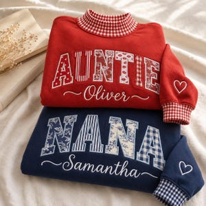 May include: A red sweatshirt with a red and white gingham collar and cuffs, featuring the word AUNTIE in patterned letters and the name Oliver, plus a navy blue sweatshirt with a blue and white gingham collar and cuffs, featuring NANA and Samantha.