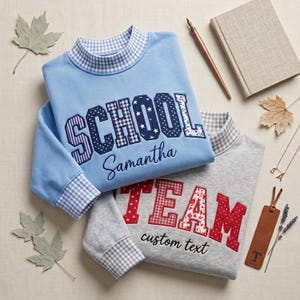 May include: A light blue sweatshirt with a blue and white gingham collar and cuffs, featuring the word SCHOOL in patterned applique letters and the name Samantha. A grey sweatshirt with a grey gingham collar and cuffs, featuring the word TEAM in red patterned applique letters and the text custom text.
