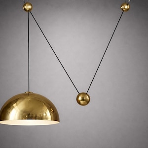 Peut inclure: Suspension luminaire moderne de couleur dorée avec un abat-jour hémisphérique. La lumière est suspendue à un cordon noir, soutenu par des sphères dorées. Design minimaliste et élégant, pour l'éclairage intérieur.