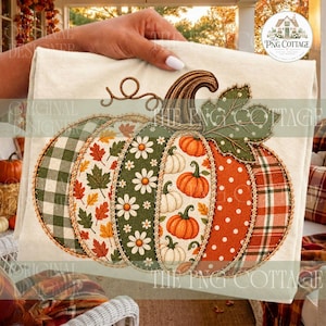 May include: A cream-colored fabric square featuring a large, multi-patterned pumpkin applique. The pumpkin is divided into vertical sections with green gingham, autumn leaves, white daisies, orange pumpkins, white polka dots, and plaid patterns.
