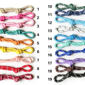 May include: Nineteen loops of braided cord in various colours, each featuring a white reflective thread pattern. The cords are arranged in two vertical columns and numbered 1 through 19, showcasing shades including beige, pink, teal, orange, yellow, red, green, blue, purple, brown, and black.