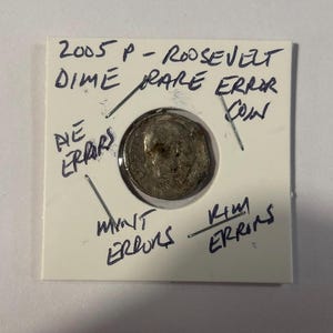 May include: A 2005 P Roosevelt dime coin, described as a rare error coin, is held in a white cardboard mount. Handwritten text includes "Die Errors," "Mint Errors," and "Kim Errins."