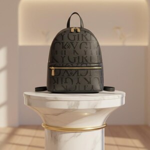 Peut inclure: Un sac à dos noir avec le texte "Y GIRL" répété. Le sac a une poignée supérieure, une poche avant zippée et des fermetures éclair dorées. Il est présenté sur un piédestal en marbre blanc avec une bande dorée.