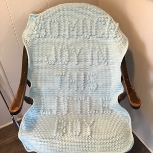 May include: A light blue crocheted baby blanket with the words "Welcome Baby Little Boy" in white.
