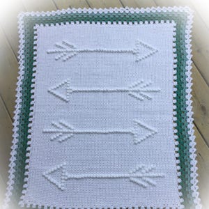 May include: White crochet baby blanket with a green border and a design of four arrows.