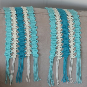 May include: Two crocheted scarves with fringe in shades of teal, turquoise, and white.