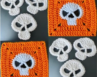 May include: White crochet skull appliques and orange crochet squares with white skull designs. The skulls are a spooky, handmade craft item, perfect for Halloween or gothic-themed projects. The image shows a close-up of the crochet work.
