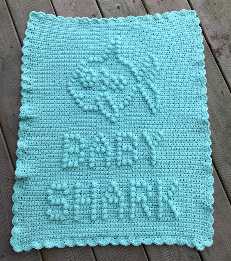 May include: A light blue crocheted baby blanket with a scalloped border and the name "Baby Savannah" written in raised stitches.