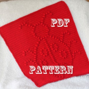 Può includere: Quadrato di uncinetto rosso con un motivo testurizzato. Il testo "PDF PATTERN" è stampato sul quadrato.