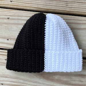 May include: A black and white crocheted beanie hat. The hat is split down the middle, with one half black and the other half white.
