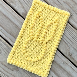May include: A yellow crocheted rectangle with a textured pattern. The crochet is made with a single crochet stitch and a bobble stitch.