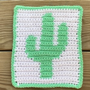 May include: A green crocheted cactus design on a white background. The cactus is outlined in green and has a green border.
