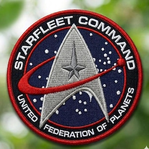 May include: Embroidered patch featuring the Starfleet Command emblem. The circular patch has a navy blue background with white stars and the text "STARFLEET COMMAND" and "UNITED FEDERATION OF PLANETS". The central emblem is a silver arrowhead with a red swoosh.