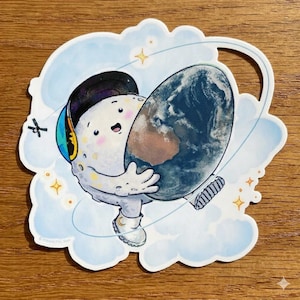 May include: A whimsical sticker featuring a cartoon moon character wearing a cap and sneakers, hugging a globe. The moon is white with a smiling face, set against a blue cloud background with stars.